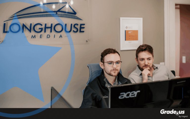 Two male agency workers looking at a computer monitor with Longhouse Media logo in background.